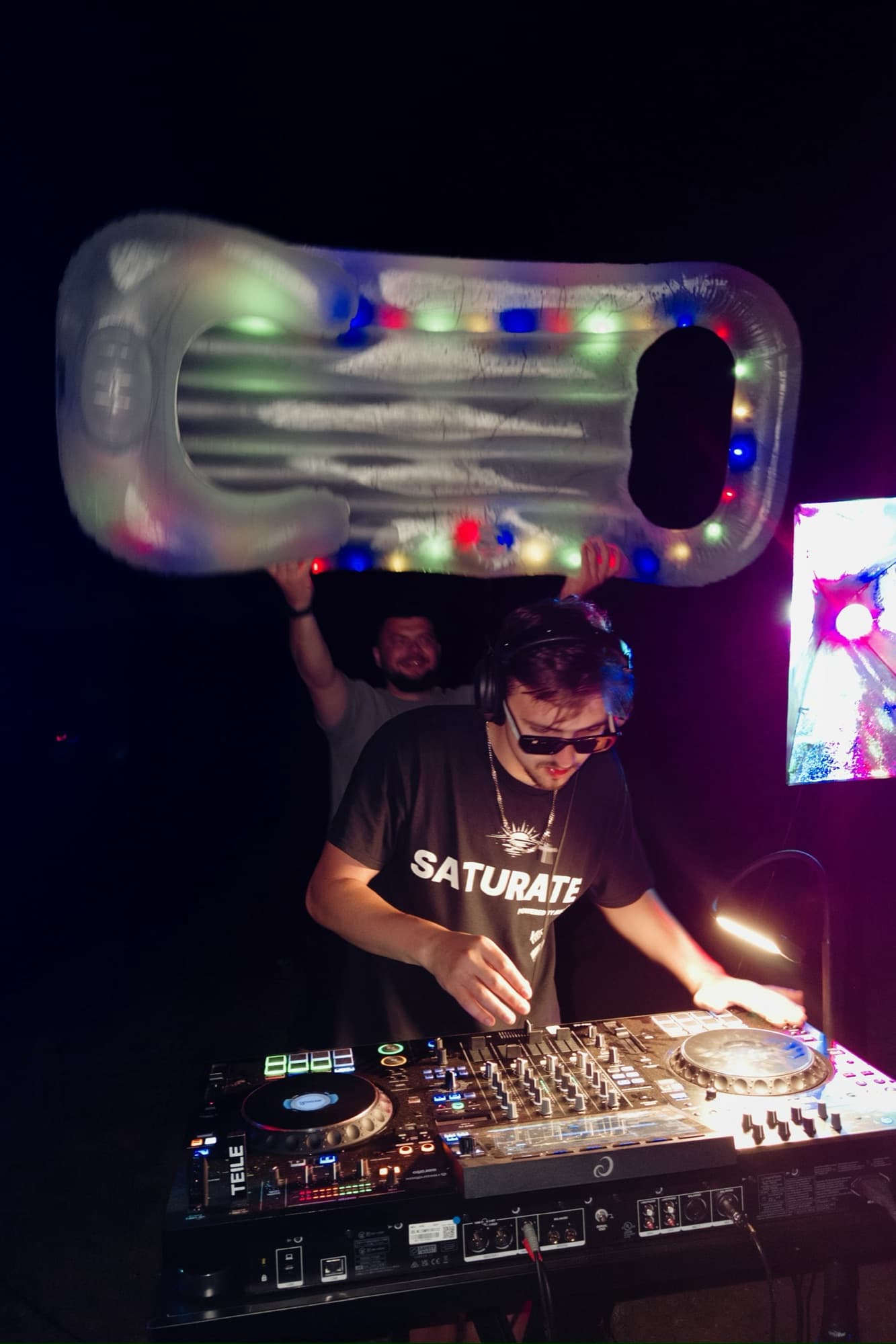 ARSKGG DJing at a party under a lit-up inflatable float