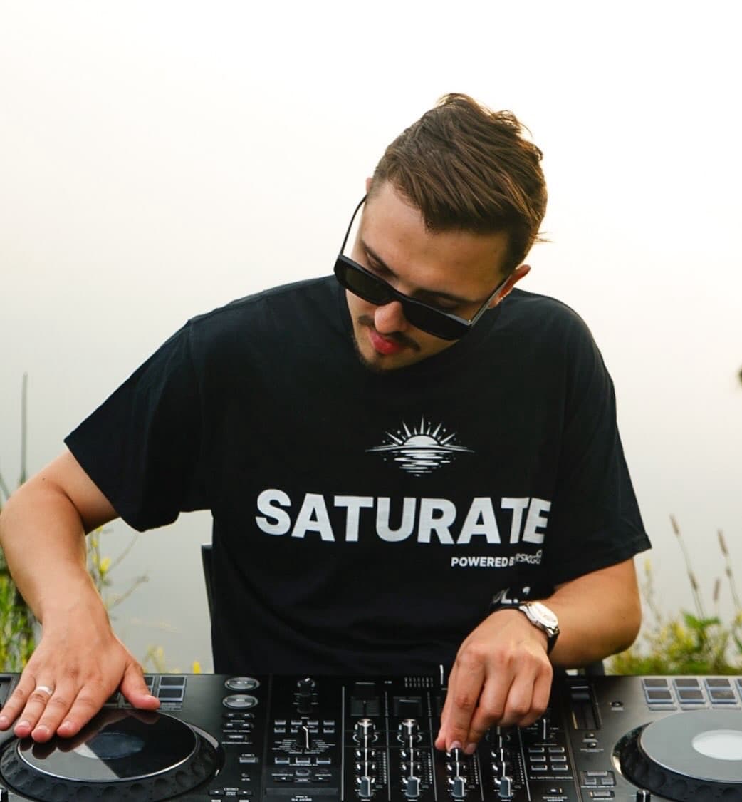 ARSKGG mixing at a lakeside set in a SATURATE t-shirt
